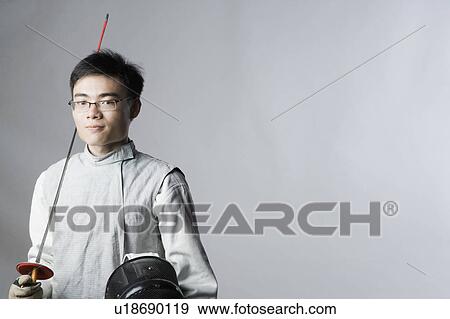Stock Photo - Portrait of a male fencer holding a sword and a fencing mask. Fotosearch