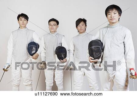 Stock Image - Portrait of four male fencers holding fencing foils and fencing masks. Fotosearch