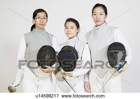Stock Photo - Portrait of three female fencers holding fencing foils and fencing masks. Fotosearch