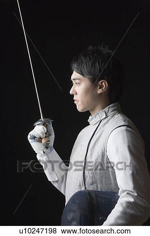 Side profile of a male fencer holding a fencing foil and a fencing mask View Large Photo Image Stock Photo - Side profile of a male fencer holding a fencing foil and a fencing mask. Fotosearch
