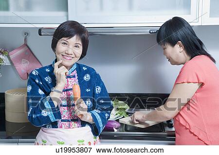 Portrait of a senior woman and her daughter preparing food in a kitchen View Large Photo Image Stock Photo - Portrait of a senior woman and her daughter preparing food in a kitchen. Fotosearch