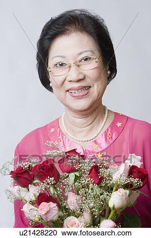 Portrait of a senior woman holding a bouquet of flowers View Large Photo Image Stock Image - Portrait of a senior woman holding a bouquet of flowers. Fotosearch