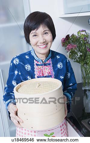 Portrait of a senior woman holding a bamboo steamer in a kitchen View Large Photo Image Stock Photograph - Portrait of a senior woman holding a bamboo steamer in a kitchen. Fotosearch