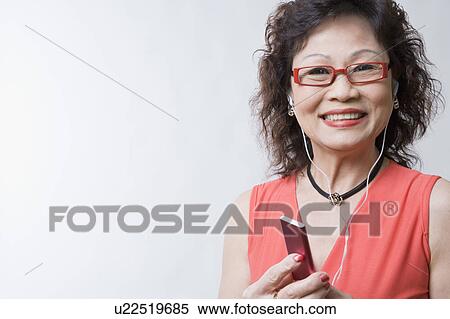 Portrait of a senior woman listening to an MP3 player and smiling View Large Photo Image Stock Photography - Portrait of a senior woman listening to an MP3 player and smiling. Fotosearch