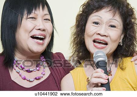 Stock Image - Portrait of a senior woman singing with a mature woman in front of a microphone. Fotosearch