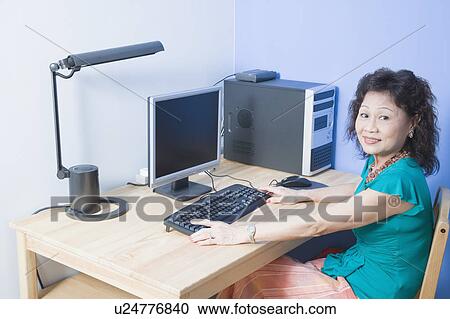 Portrait of a senior woman using a computer and smiling View Large Photo Image Stock Image - Portrait of a senior woman using a computer and smiling. Fotosearch