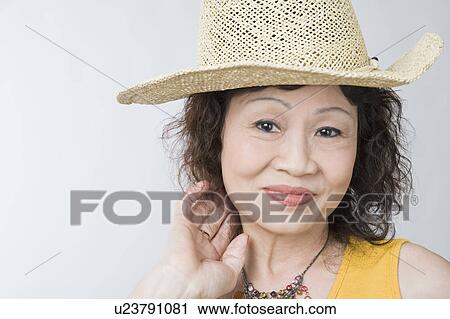 Stock Image - Portrait of a senior woman wearing a straw hat and posing. Fotosearch