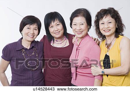 Stock Image - Portrait of three senior women and a mature woman standing together and smiling. Fotosearch