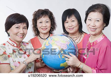 Stock Image - Portrait of three senior women and a mature woman holding a globe. Fotosearch