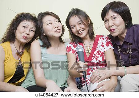 Portrait of two young women singing with their grandmothers into microphones View Large Photo Image Stock Photo - Portrait of two young women singing with their grandmothers into microphones. Fotosearch