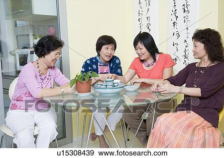 Stock Photo - Three senior women and a mature woman sitting at a table. Fotosearch