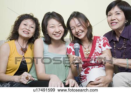 Two young women singing with their grandmothers into microphones View Large Photo Image Stock Photo - Two young women singing with their grandmothers into microphones. Fotosearch