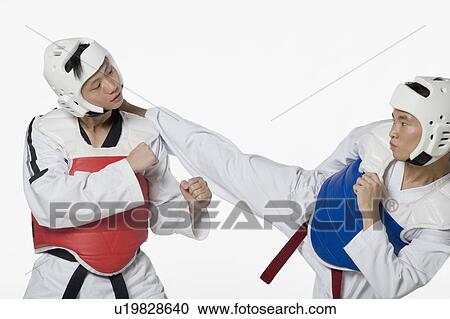 Stock Image - Close-up of a mid adult man practicing kickboxing with a young man. Fotosearch