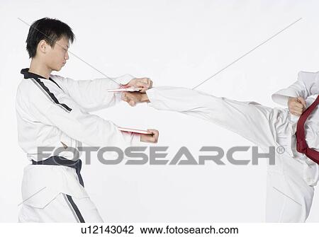 Stock Image - Low section view of a mid adult man practicing kickboxing with a young man. Fotosearch
