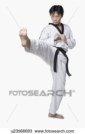 Stock Image - Mid adult man practicing front kick. Fotosearch