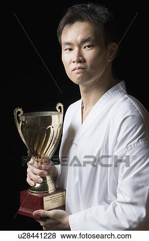 Portrait of a young man holding a trophy View Large Photo Image Stock Photo - Portrait of a young man holding a trophy. Fotosearch