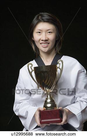 Portrait of a young woman holding a trophy View Large Photo Image Stock Photo - Portrait of a young woman holding a trophy. Fotosearch