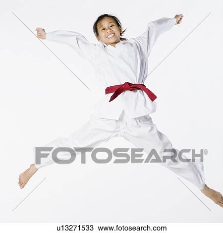 Stock Image - Portrait of a young woman jumping and practicing martial arts. Fotosearch