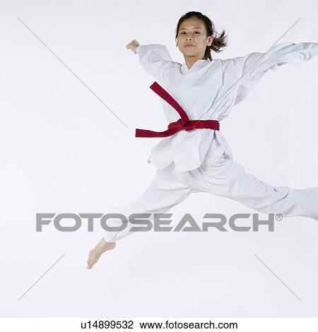Stock Image - Portrait of a young woman jumping and practicing martial arts. Fotosearch