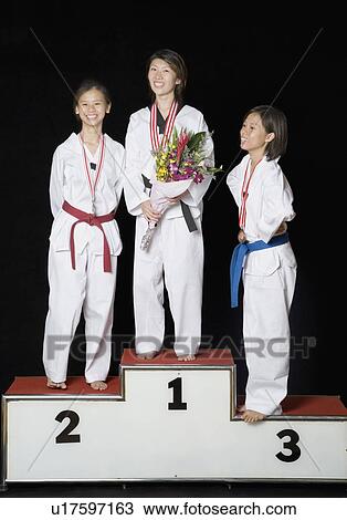 Three young women standing on a winners podium with their medals View Large Photo Image Stock Image - Three young women standing on a winners podium with their medals. Fotosearch