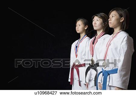 Stock Photo - Three young women standing with their medals. Fotosearch