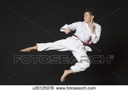 Stock Photo - Young man performing flying kick. Fotosearch
