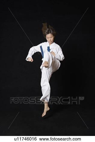 Stock Photograph - Young woman performing front kick. Fotosearch