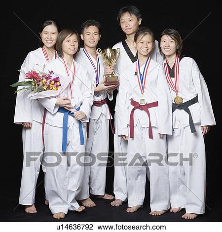 Stock Image - Group of martial arts players standing with their medals and trophies. Fotosearch