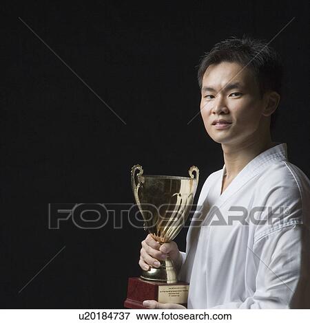 Portrait of a young man holding a trophy View Large Photo Image Stock Photo - Portrait of a young man holding a trophy. Fotosearch