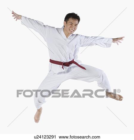 Stock Image - Portrait of a young man jumping and practicing martial arts. Fotosearch