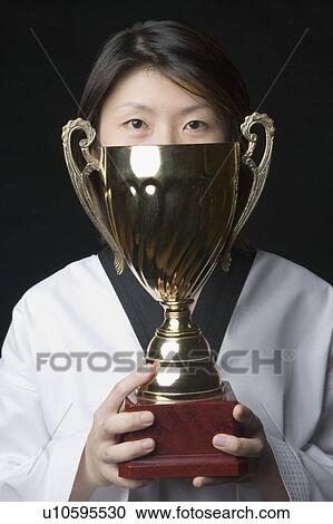 Portrait of a young woman holding a trophy View Large Photo Image Stock Image - Portrait of a young woman holding a trophy. Fotosearch