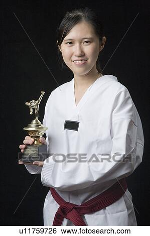 Stock Photograph - Portrait of a young woman holding a trophy and smiling. Fotosearch