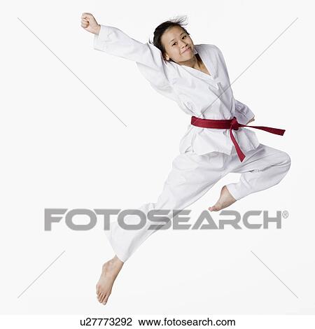 Stock Image - Portrait of a young woman jumping and practicing martial arts. Fotosearch