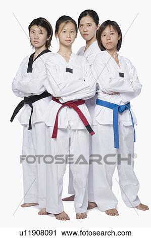 Stock Image - Portrait of four young women standing with their arms crossed. Fotosearch