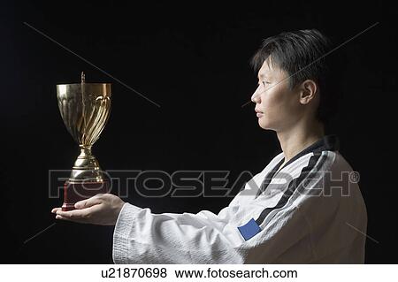 Side profile of a young man holding a trophy View Large Photo Image Stock Photo - Side profile of a young man holding a trophy. Fotosearch