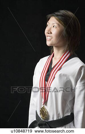 Stock Photo - Young woman standing with a medal around her neck. Fotosearch
