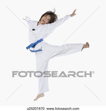 Stock Image - Close-up of a young woman jumping and practicing martial arts. Fotosearch