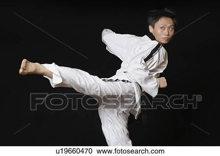 Mid adult man performing the side kick View Large Photo Image Stock Image - Mid adult man performing the side kick. Fotosearch