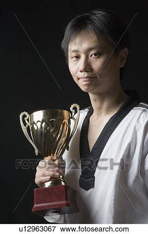 Portrait of a young man holding a trophy View Large Photo Image Stock Photo - Portrait of a young man holding a trophy. Fotosearch