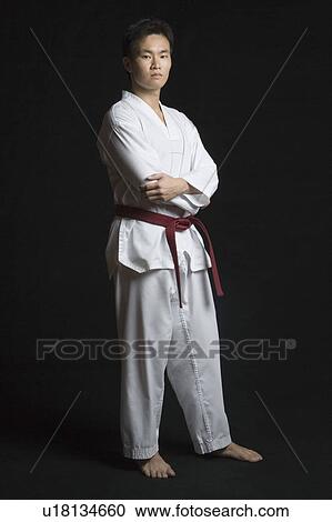 Stock Image - Portrait of a young man standing with his arms crossed. Fotosearch