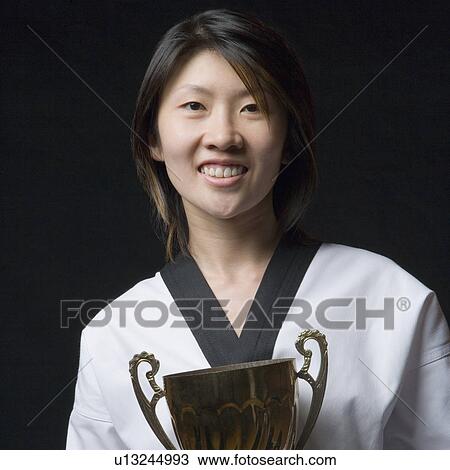 Portrait of a young woman holding a trophy View Large Photo Image Stock Image - Portrait of a young woman holding a trophy. Fotosearch