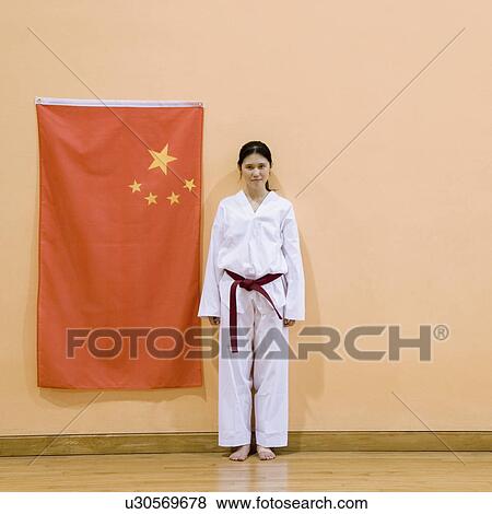 Stock Photo - Portrait of a young woman standing near a Chinese flag. Fotosearch