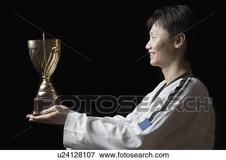 Side profile of a young man holding a trophy and smiling View Large Photo Image Stock Photo - Side profile of a young man holding a trophy and smiling. Fotosearch