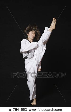 Stock Image - Young woman performing front kick. Fotosearch