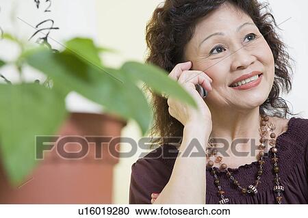 Stock Image - Close-up of a senior woman using a mobile phone and smiling. Fotosearch