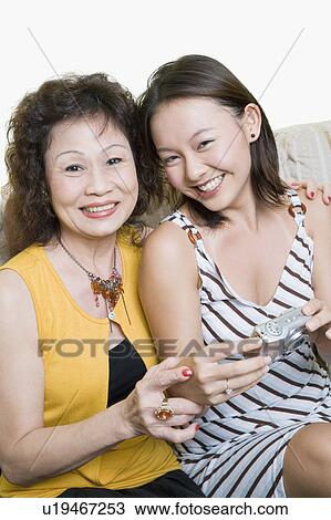 Stock Image - Portrait of a senior woman and her granddaughter sitting together and smiling. Fotosearch