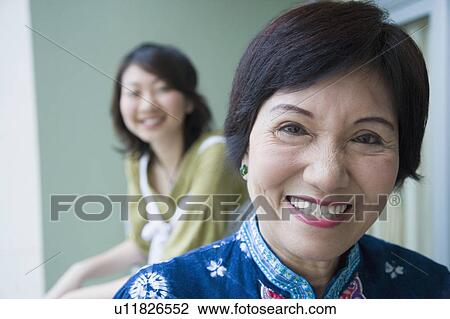 Stock Image - Portrait of a senior woman smiling with her granddaughter standing behind her. Fotosearch