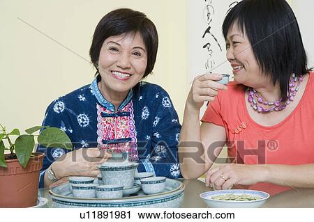Stock Image - Portrait of a senior woman smiling with a mature woman sitting beside her. Fotosearch