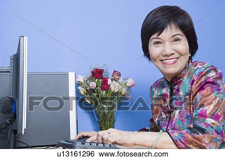 Stock Photograph - Portrait of a senior woman using a computer and smiling. Fotosearch
