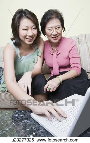 Senior woman and her granddaughter using a laptop and smiling View Large Photo Image Stock Photography - Senior woman and her granddaughter using a laptop and smiling. Fotosearch
